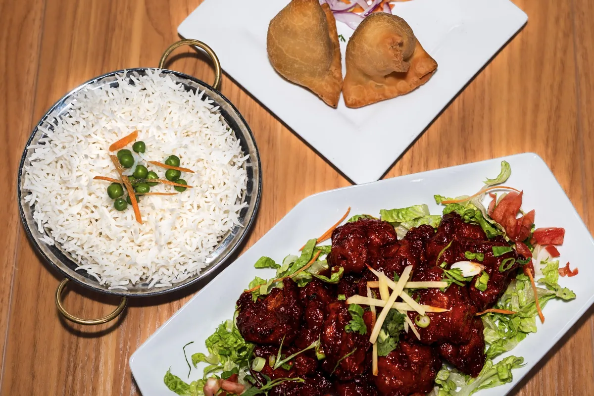 A Lilly's party pack spread: hand-folded samosas, chili chicken, and steamed basmati rice